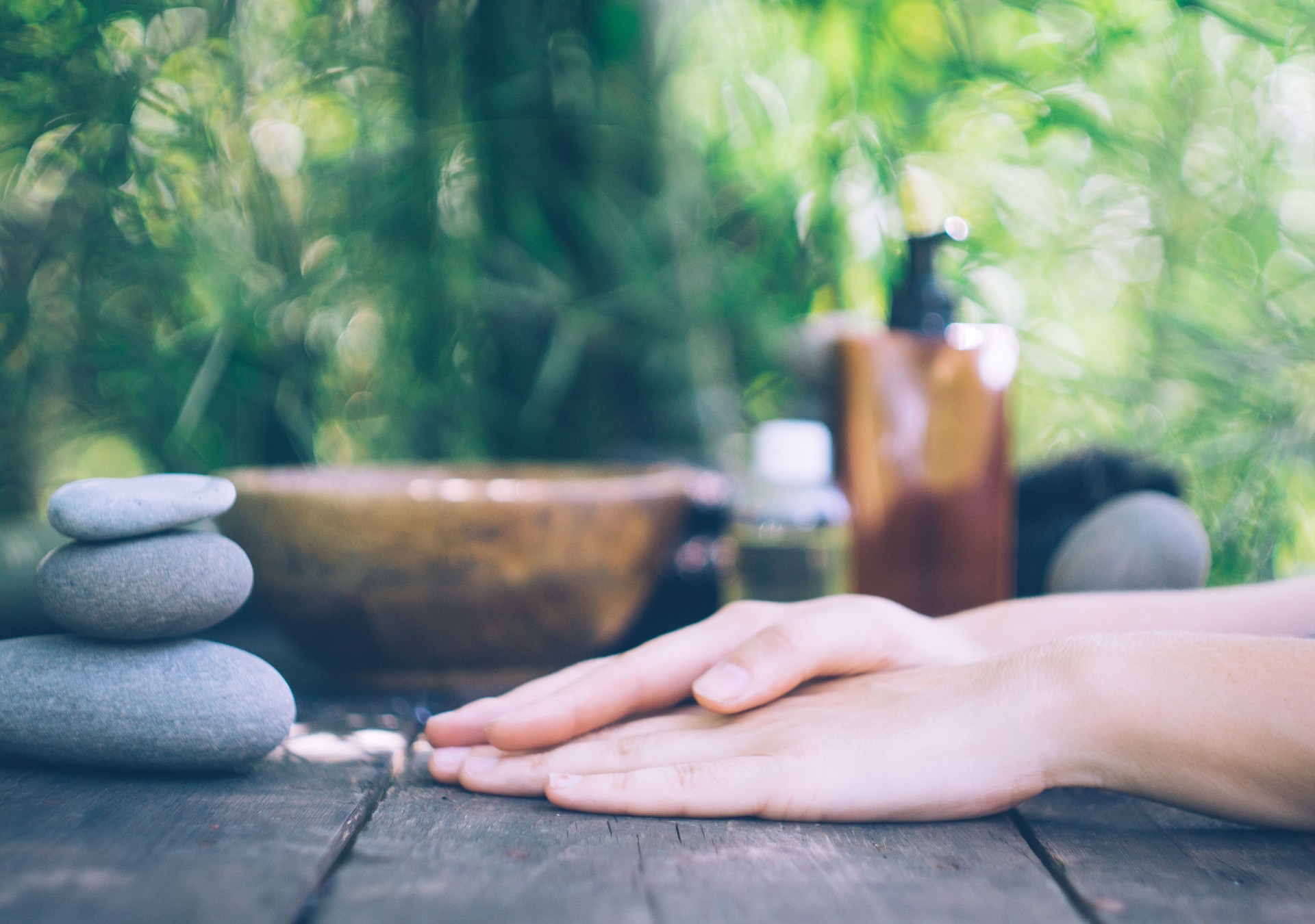 Bamboo manicure spa concept: massage oil, towels and warm stones on an old wooden table. Zen, relax and peaceful mood